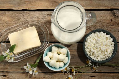 Farklı taze süt ürünleri ve çiçekler ahşap masada, düz yatıyordu.
