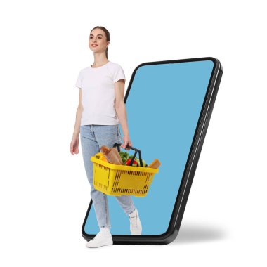 Elinde alışveriş sepeti dolusu mal olan bir kadın beyaz arka planda cep telefonundan çıkıyor. Çevrimiçi sıralama