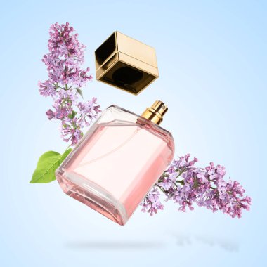 Bir şişe çiçek parfümü ve açık mavi arka planda çiçek açan leylak.