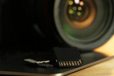 SD hafıza kartları, dizüstü bilgisayar ve fotoğraf makinesi ahşap masada, yakın plan.