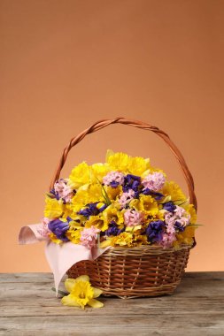 Tahta masada mercan zemin üzerinde güzel çiçeklerle dolu bir sepet.