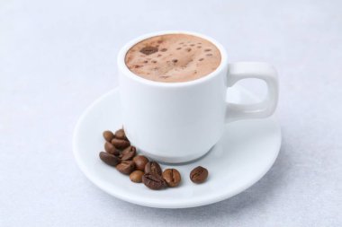 Aromatik kahve fincanda, fasulye ve çay tabağı ışık masasında, yakın plan.