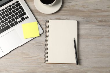 Defter, kalem, yapışkan not, sehpadaki kahve ve dizüstü bilgisayar, düz konum