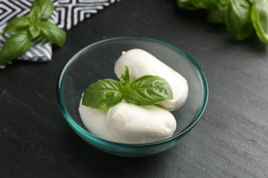 Lezzetli mozzarella peyniri ve fesleğen parçaları koyu dokulu masada, yakın plan.