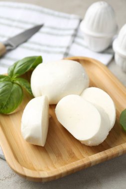 Lezzetli mozzarella peyniri ve fesleğen yaprakları. Gri desenli masa, yakın plan.