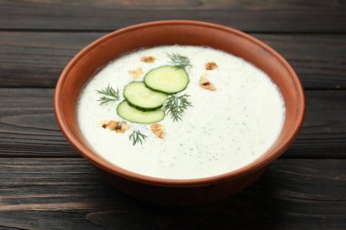 Ahşap masada dereotlu ve cevizli lezzetli salatalık çorbası, yakın plan.