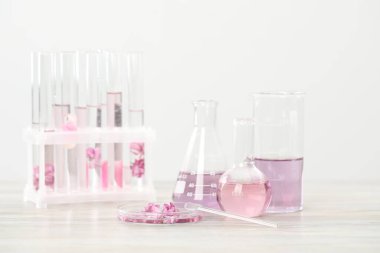 Lüks parfüm yapıyorum. Temel yağlar cam süslemede ve çiçekler beyaz ahşap masada, yakın plan.