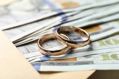 İki altın alyans, dolar banknotları ve zarf, yakın plan.