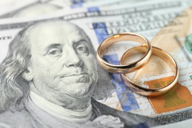 Dolar banknotları üzerinde iki altın alyans, yakın plan.