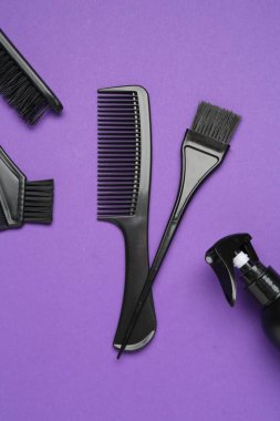 Mor arka planda farklı kuaför aletleri, düz yatış