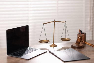 Yargıç. Dizüstü bilgisayar, tokmak, terazi ve pano ofisteki ahşap masada.