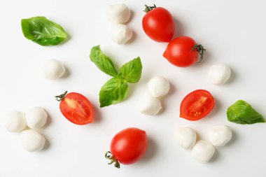Beyaz arka planda lezzetli mozzarella topları, domatesler ve fesleğen.