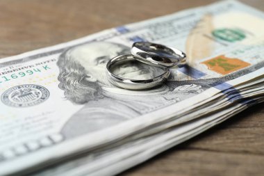 Gümüş alyanslar ve dolar banknotları ahşap masada, yakın plan.