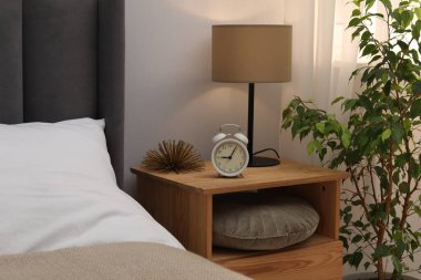 İçinde lamba, çalar saat ve yatağın yanında dekor olan komodin. İç tasarım