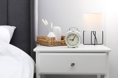 İçinde lamba, çalar saat ve yatağın yanındaki dekorun bulunduğu komodin.