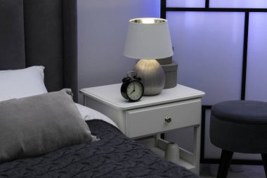 İçinde lamba, çalar saat ve yatağın yanındaki dekorun bulunduğu komodin.