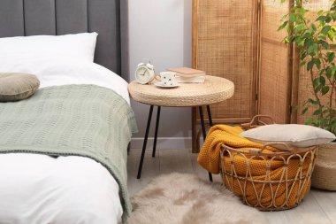 Çalar saati olan yan masa, yatağın yanında bir bardak içki ve dekor.