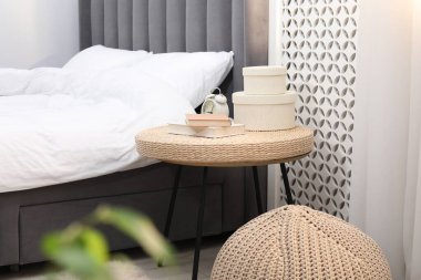 Çalar saati, kitapları ve yatağın yanında dekorasyonu olan yan masa.