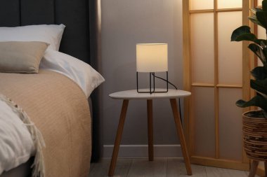 Yan masada yatağın yanında lamba var.