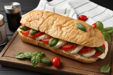 Mozarella peynirli, domatesli, fesleğenli, siyah ahşap masa, yakın plan.