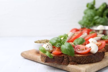 Mozarella peynirli, domatesli, fesleğenli ve baharatlı lezzetli sandviçler açık fayanslı masada, yakın plan. Metin için boşluk
