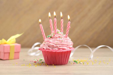 Kekin içinde mum yakmak, şeker serpmek ve ahşap masada parti dekorasyonu yapmak.