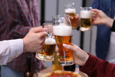 Arkadaşlar bira bardaklarını tokuşturur, yakın plan