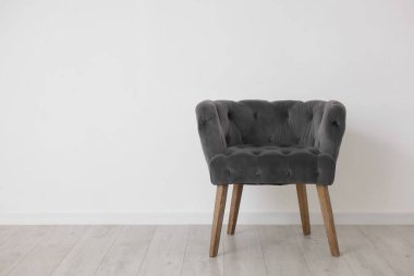 Beyaz duvarın yanındaki rahat gri koltuk, metin için boşluk.