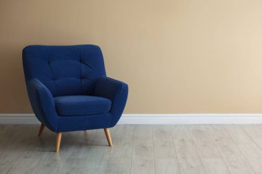 Bej duvarın yanında rahat, yumuşak mavi koltuk, metin için yer var.