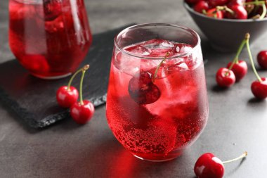 Buzlu vişneli gazoz ve bardaklar gri masada, yakın plan.