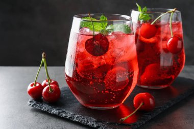 Buzlu vişneli gazoz, böğürtlen ve nane şekeri. Gri masada, yakın plan.