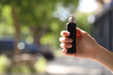 Dışarıda elektronik sigara içen genç bir kadın, yakın plan. Metin için boşluk