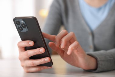 İçerideki masada akıllı telefon kullanan kadın, yakın plan.