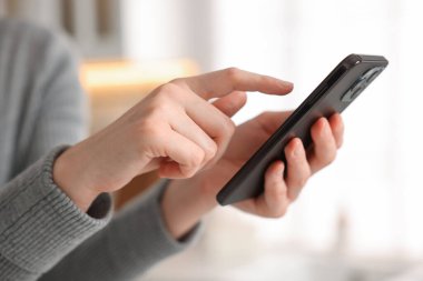 Evde modern akıllı telefon kullanan bir kadın, yakın plan.