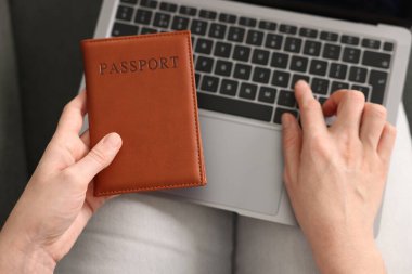 Pasaportu olan bir kadın ev içi bilgisayar kullanıyor.