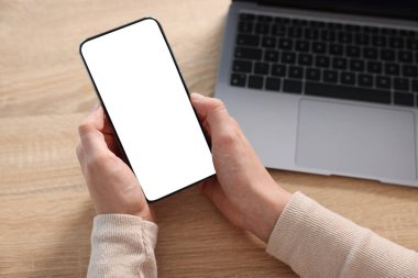 Ahşap masada modern akıllı telefon kullanan bir kadın.