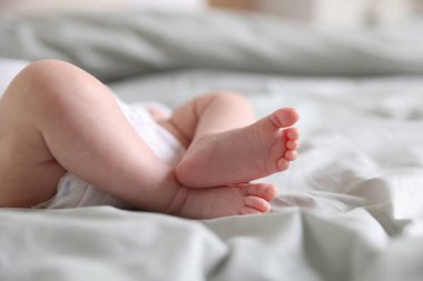 Sevimli yeni doğmuş bebek yatakta uzanıyor, yakın plan.