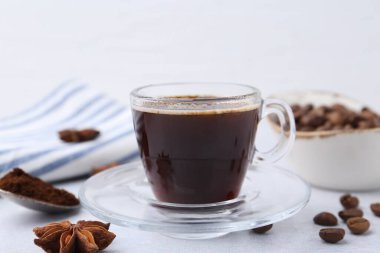 Bir fincan aromatik kahve, fasulye ve yıldız anason beyaz masada, yakın plan.