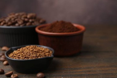 Kahverengi arka planda, ahşap masada farklı kahve ve fasulye türleri, yakın plan.