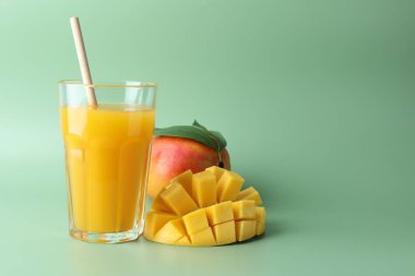 Bardakta lezzetli mango suyu ve yeşil arka planda taze meyve, metin için yer