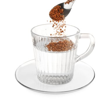 Beyaz üzerine izole edilmiş sıcak su ile granüle edilmiş hazır kahveyi fincana koymak.