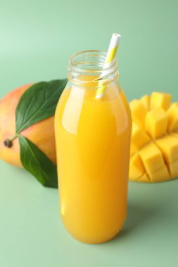 Cam şişede lezzetli mango suyu ve yeşil arka planda taze meyve, yakın plan.