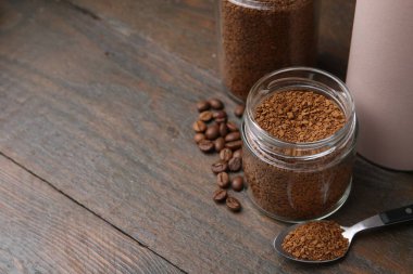 Kavanozlarda hazır kahve ve ahşap masada fasulye, yakın plan. Metin için boşluk