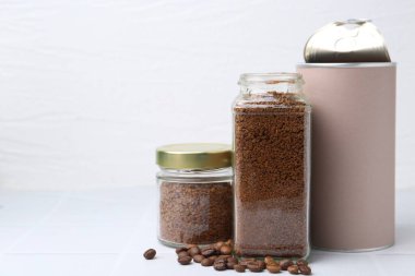 Kavanozlarda kahve ve beyaz fayanslı masada fasulye, yakın plan. Metin için boşluk