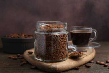 Cam kavanozdaki anlık kahve, sıcak içecek ve ahşap masada fasulye, yakın plan.