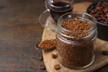 Cam kavanozdaki anlık kahve, sıcak içecek ve ahşap masada fasulye, yakın plan. Metin için boşluk