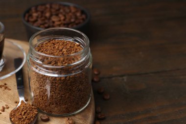 Cam kavanozda anında kahve ve ahşap masada fasulye, yakın plan. Metin için boşluk