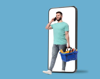 Cep telefonundan çıkan bir sepet dolusu ürünle açık mavi arka planda yürüyen bir adam. Çevrimiçi sıralama