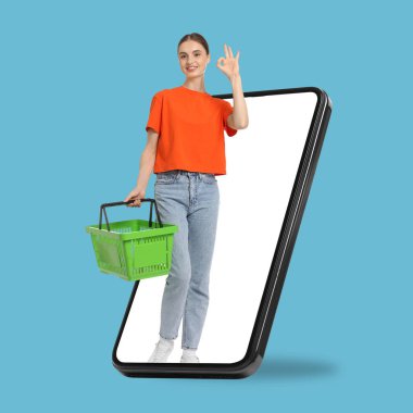 Alışveriş sepetli bir kadın açık mavi arka planda cep telefonundan iyi görünüyor. Çevrimiçi sıralama