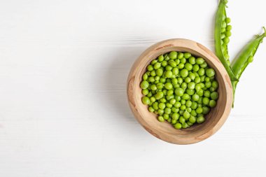 Beyaz ahşap masada taze taze taze bezelyeler, üst manzara. Metin için boşluk